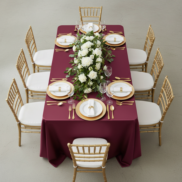 Lamour Satin 90"x156" Rectangular Oblong Tablecloth - Burgundy top view with gold charger plate | white dinner plate | white napkin | gold chiavari chair