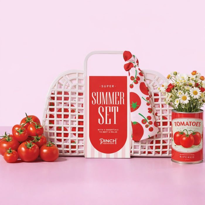 Pinch Provisions Super Summer Set with tomatoes, flowers, and pink woven baskets on pink background