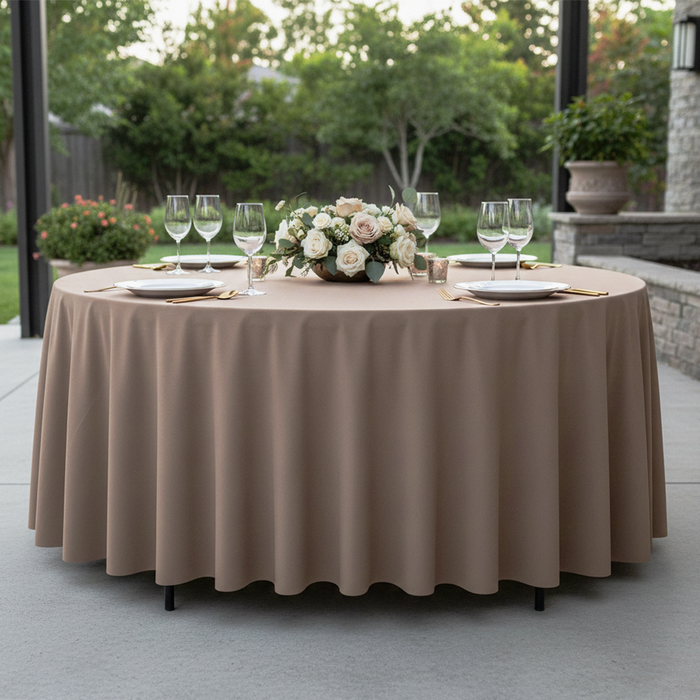 Premium Polyester 90" Round Tablecloth Taupe paired with wine goblets, floral centerpiece, white charger plates and gold silverware