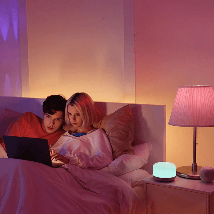A man and woman laying in bed with a laptop between them.